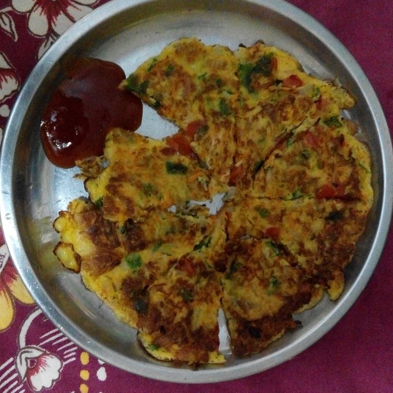 Egg paratha cut into wedges on a steel plate with ketchup