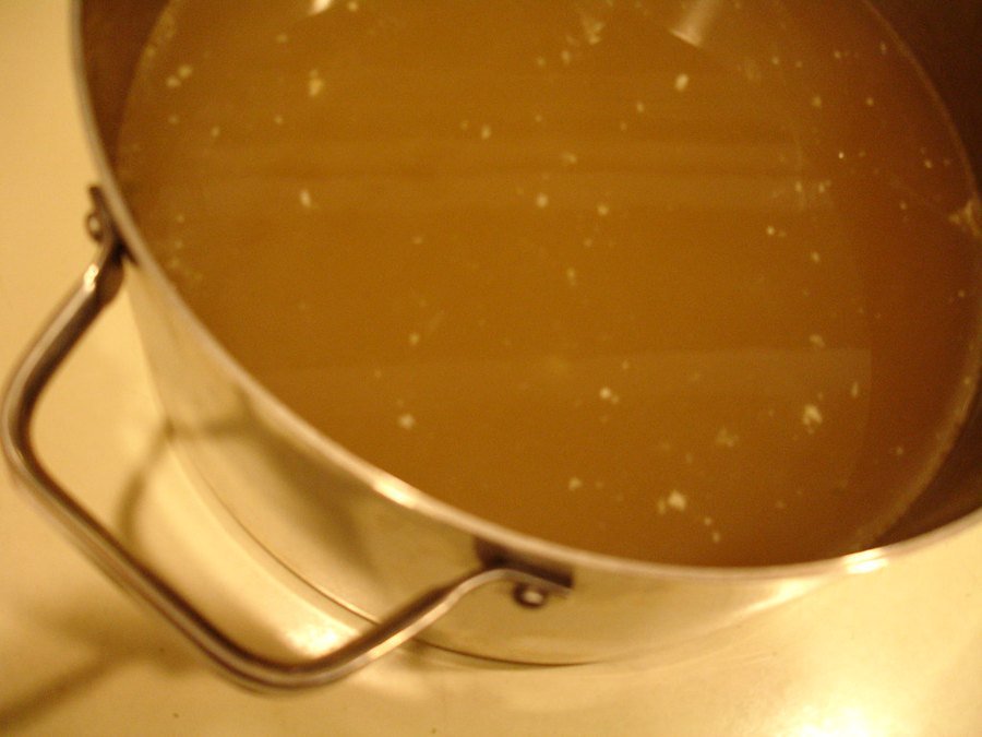 A pot of clear, golden homemade chicken stock